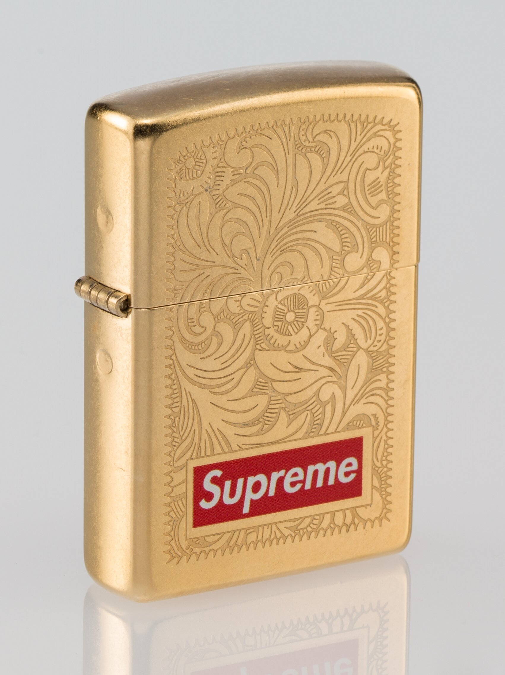 Supreme X Zippo. Lighter, c. 2011. Golden zippo lighter with | Lot 